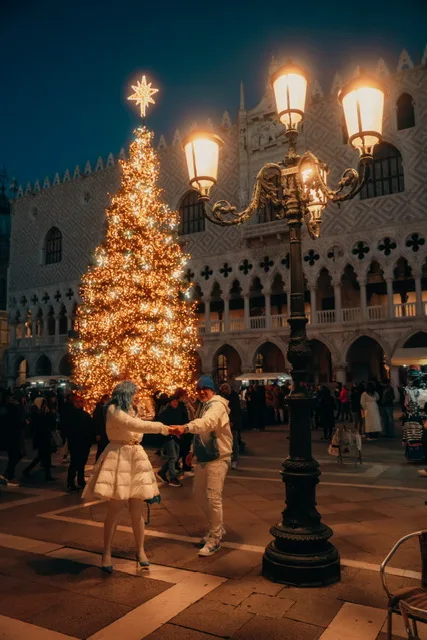Michi und Silvio tanzen vor dem beleuchteten Weihnachtsbaum auf dem Markusplatz